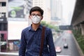 Young Asian man wearing N95 respiratory mask protect and filter pm2.5 particulate matter against traffic and dust city.