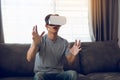 Young asian man wearing virtual reality glasses at living room for admiring virtual reality Royalty Free Stock Photo