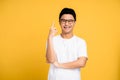 Young Asian man wearing a white T-shirt and glasses. He pointed a finger with a happy face. Isolated background