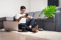 Young Asian man working from home and chatting with smartphone after working by using laptop computer. Work from home concept Royalty Free Stock Photo