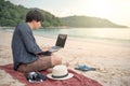 Young Asian man working with laptop on the beach Royalty Free Stock Photo