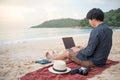 Young Asian man working with laptop on the beach Royalty Free Stock Photo