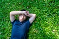 Young asian men lies on green moss relaxing with eyes closed and hands behind his head, feeling comfortable on the grass field Royalty Free Stock Photo