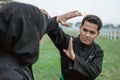 Young Asian men wearing pencak silat uniforms with a deflection movement and women wearing a hijab with hitting