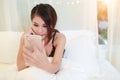 Young asian model with black see through dress holding cell phone on bed Royalty Free Stock Photo