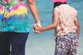 Young asian mother and cute little daughter holding hand together on the beach Royalty Free Stock Photo