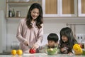 young asian mother making salad watched by her two children Royalty Free Stock Photo