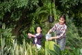 Young Asian mother and daughter happy working in the gardern together on weekend. Daughter helping mother watering