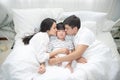 Young asian mother, father and boy sleeping in bed, mom and dad kiss on cheek of son,view from above Royalty Free Stock Photo