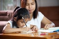 Young asian mother helping her daughter do her homework at home. Royalty Free Stock Photo