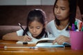 Young asian mother helping her daughter do her homework at home. Royalty Free Stock Photo