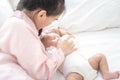 Young asian mother hold in arms and feed baby newborn from milk bottle. Portrait cute newborn baby being fed by mother using Royalty Free Stock Photo