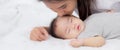 Young asian mother kiss cheek of little baby girl with tender on bed in the bedroom, mom love newborn and care. Royalty Free Stock Photo