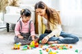 Young asian mother and little daughter enjoy to play puzzle wood toy together in area of living room of their house and they look Royalty Free Stock Photo