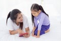 Young asian mother and little daughter looking tablet computer together for learning and education on bed in bedroom. Royalty Free Stock Photo