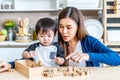 Young asian mother and little son enjoy to play wooden jigsaw puzzle together in area of kitchen of their house and they look