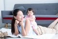 Young Asian mother lying on floor, giving cute 7 month newborn baby girl piggyback ride, enjoying active leisure time. Smiling Royalty Free Stock Photo