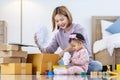 Young Asian mother is packing her merchandise product package while working at home ready to deliver while her toddler kid is Royalty Free Stock Photo