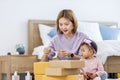 Young Asian mother is packing the merchandise product package while working at home ready to deliver while her toddler kid is Royalty Free Stock Photo