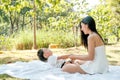 Young Asian mother play and fun with her little boy on white carpet in the green garden with morning light Royalty Free Stock Photo