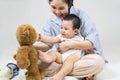 Young Asian mother playing teddy bear toy with her baby boy at home. Happy family play and learn fine motor development Royalty Free Stock Photo