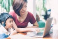 Young asian mother and son using laptop computer for study and learning together at home, boy wearing headphone. Royalty Free Stock Photo