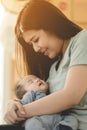 Asian Mother Cuddling Baby Daughter At Home In Front Of Window Royalty Free Stock Photo