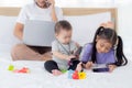 Young asian mother working at home online to internet with laptop computer and talking phone and daughter looking tablet. Royalty Free Stock Photo