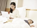 Young asian mother working on bed Royalty Free Stock Photo