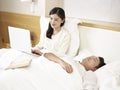 Young asian mother working on bed with sleeping daughter by side Royalty Free Stock Photo