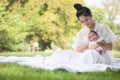 Young Asian mothers or single mom are smiling and hugging newborn babies. Family doing activities and relaxing in the park.