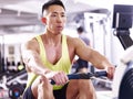 Young asian man working out using rowing machine Royalty Free Stock Photo