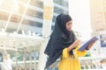 Young asian muslim business woman smiling and holding file document and standing at capital city. Royalty Free Stock Photo