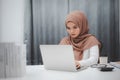 Young asian muslim businesswoman in smart casual wear sitting and working with laptop computer at home