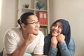 Young Asian muslim couple relaxing in their new home, looking thinking and smiling, imagining dreaming their future, husband wife Royalty Free Stock Photo