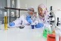 Young Asian muslim female scientist wearing safety glasses holding blue reagent dropper with beaker