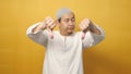 Young asian muslim man shows upset expression with thumbs down, against yellow background