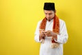 Young Asian Muslim man wearing moslim clothes holding mobile phone look at phone screen