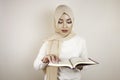 Young Asian Muslim woman wearing head scarf reading the Quran Royalty Free Stock Photo