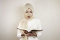 Young Asian Muslim woman wearing head scarf reading the Quran Royalty Free Stock Photo