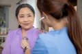 Young asian nurse or caregiver sitting on sofa holding stethoscope listen heartbeat with senior woman in living room. Royalty Free Stock Photo