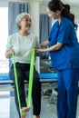 A young Asian nurse at a nursing home takes care of a senior woman. The attending physician provides physical therapy services