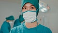 Young Asian nurse woman looking at camera and smiling after performing invasive surgery on patient in hospital operating room. Royalty Free Stock Photo