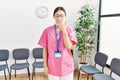 Young asian nurse woman at medical waiting room bored yawning tired covering mouth with hand Royalty Free Stock Photo