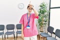 Young asian nurse woman at medical waiting room making fun of people with fingers on forehead doing loser gesture mocking and Royalty Free Stock Photo