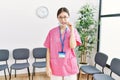 Young asian nurse woman at medical waiting room mouth and lips shut as zip with fingers