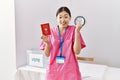 Young asian nurse woman at political campaign election holding japan passport screaming proud, celebrating victory and success Royalty Free Stock Photo