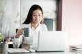 Young asian office woman working with laptop computer and holding coffee cup at desk office background, Office lifestyle concept