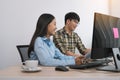 Young asian partner programmers working in team while making a new computer codes on desktop computer in the office