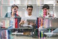 young asian people are using different gadgets and smiling, sitting near white wall. Male and female students studying using Royalty Free Stock Photo